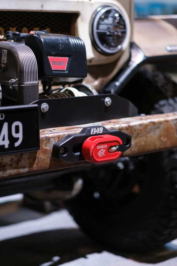 Close-up of the red Saber AWS Short mounted next to a WARN winch on the FJ49's front bumper