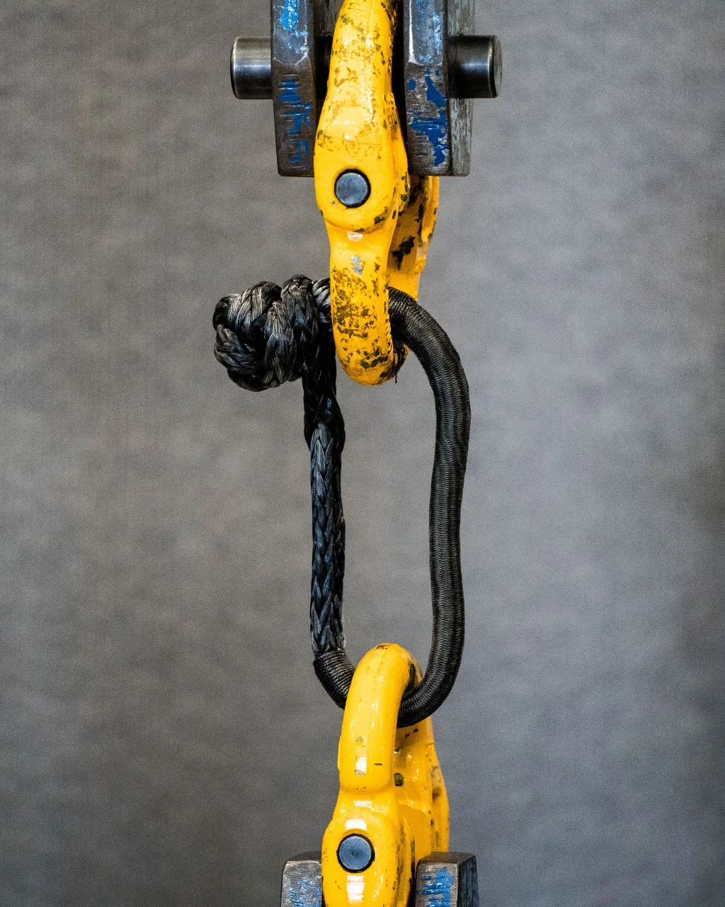 Saber soft shackle rigged into a yellow hydraulic pull-test machine ahead of a destructive breaking-strength test